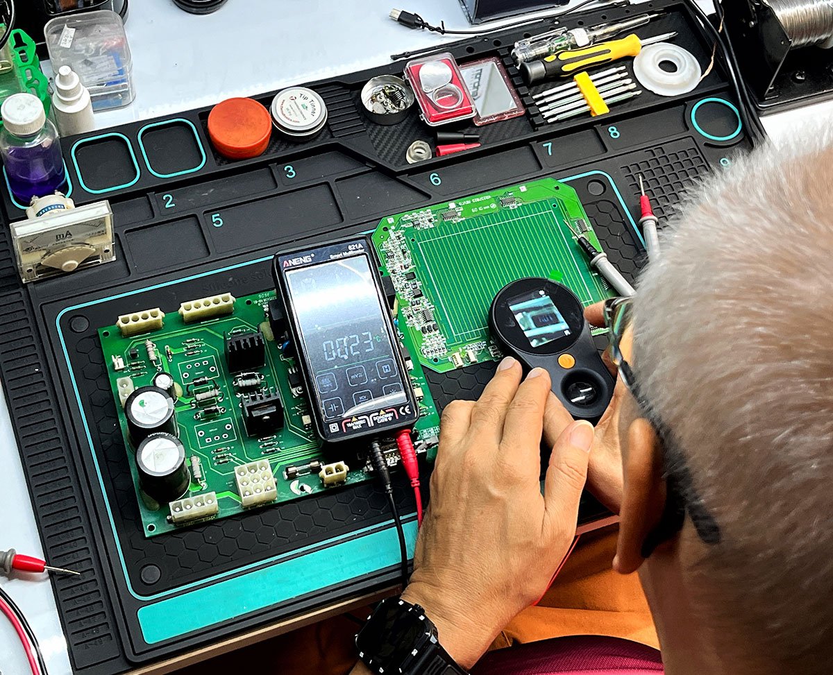 Hombre reparación una tarjeta electrónica de una máquina bordadora